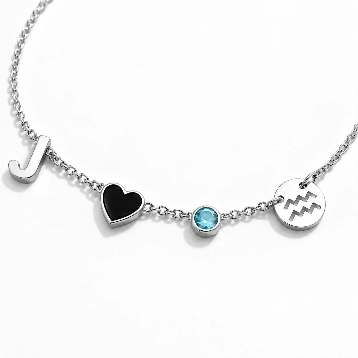 Silver necklace with J, black heart, blue birthstone and Aquarius